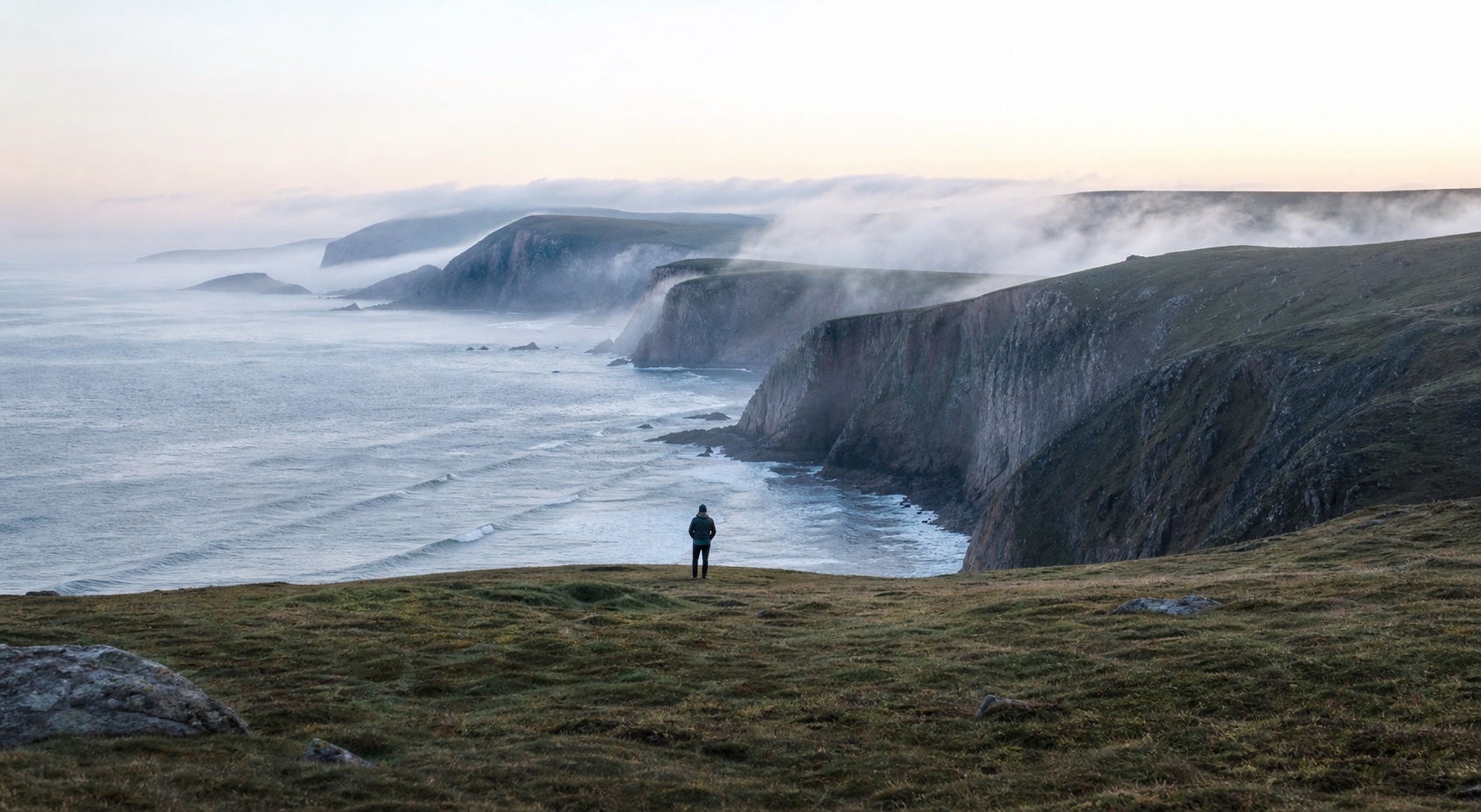 A person looking across a misty coastal headland